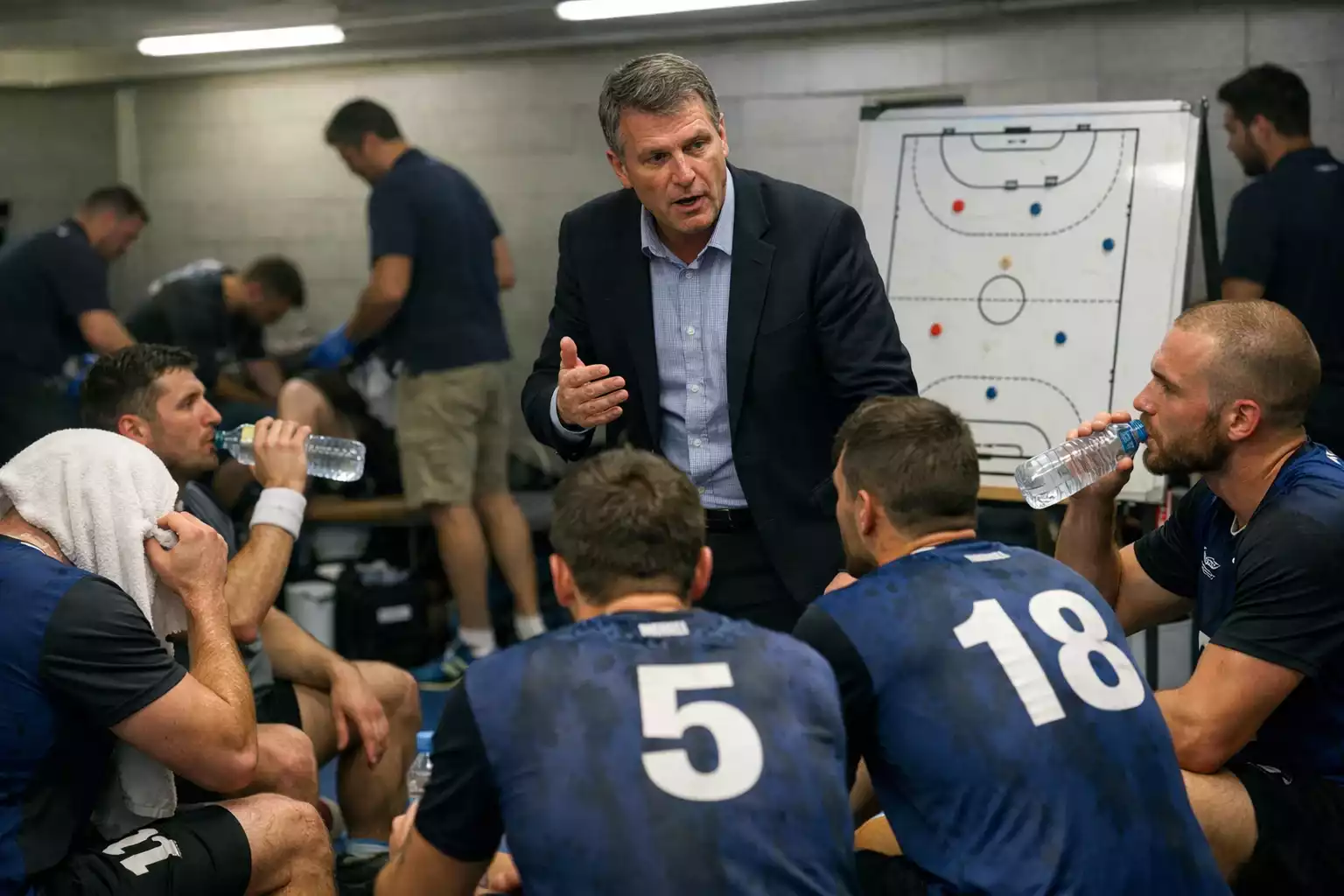 Handball-Team in der Halbzeitpause mit Trainer bei taktischer Besprechung